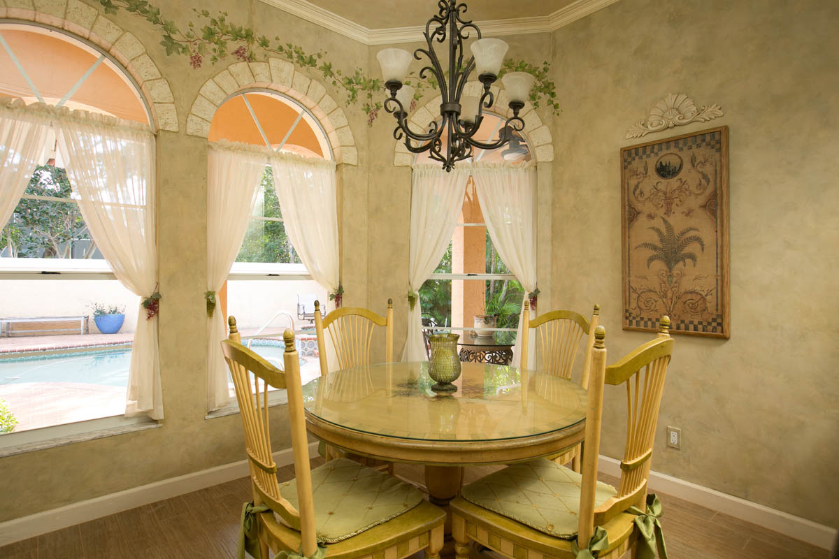 The breakfast nook with decorative painted walls and faux stone arches around the windows.      