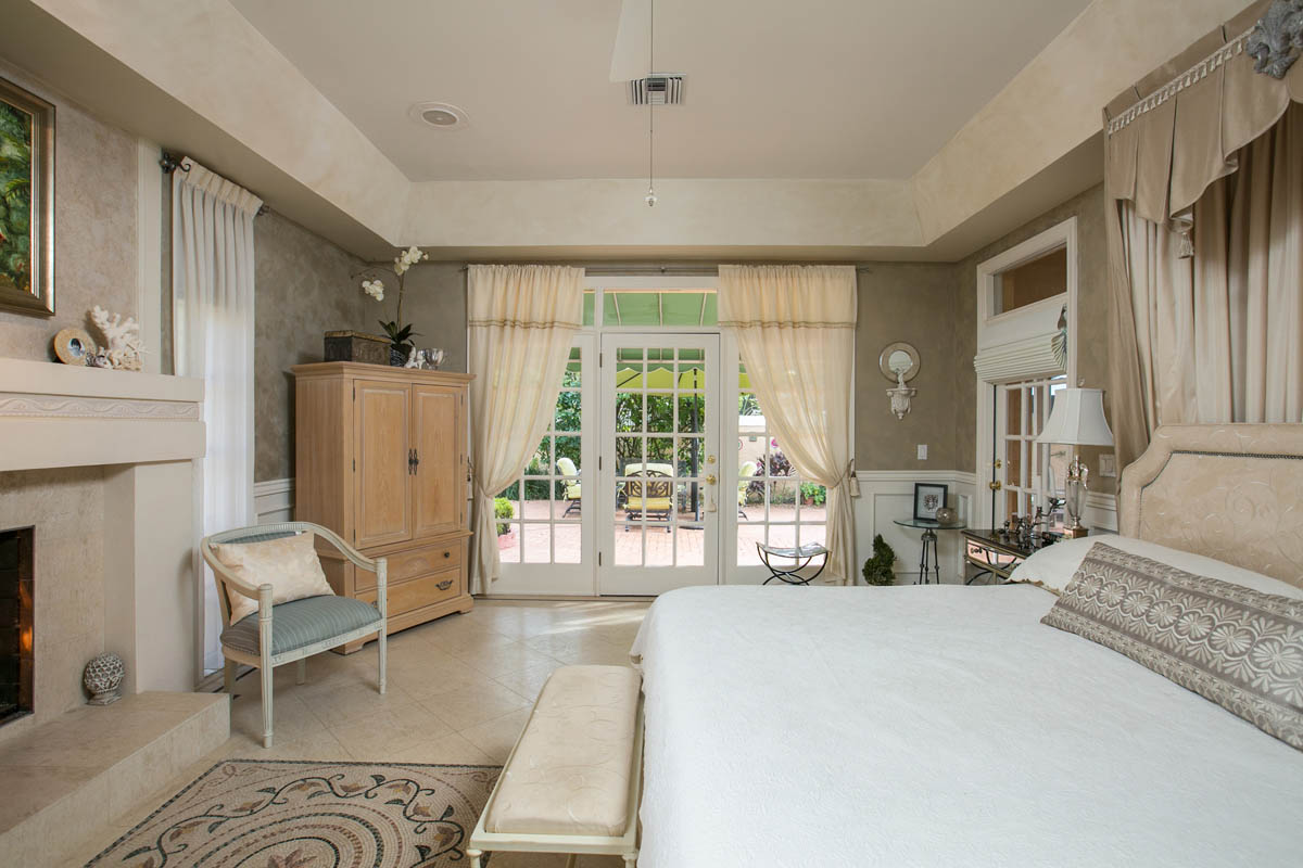 The master suite also features travertine tile floors with decorative border, a custom embedded mosaic in front of the fireplace and French doors opening to the pool patio.  