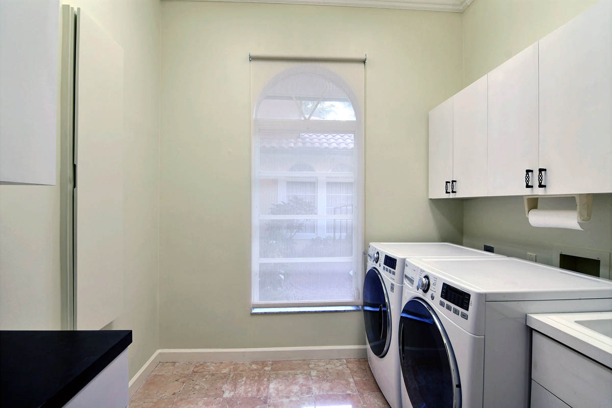 Laundry room with plenty of cabinets, pull down iron board and utility sink.              