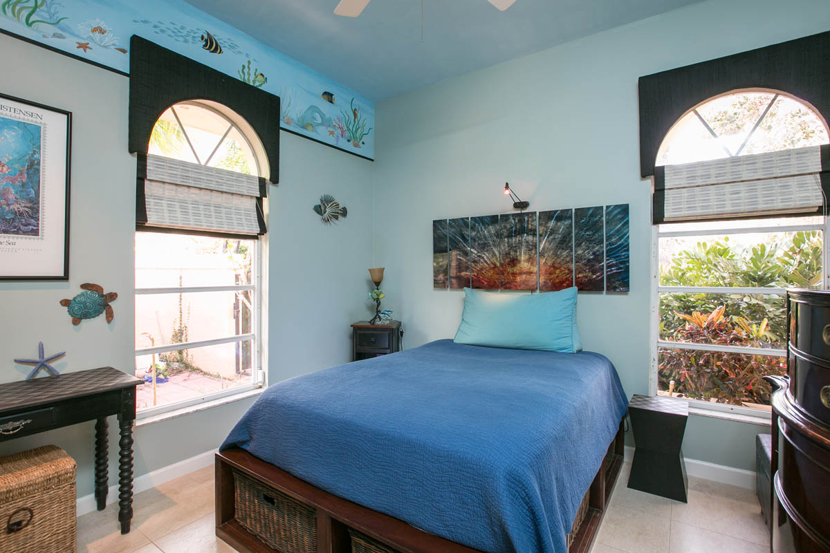 The second bedroom has travertine tile floors and offers garden views and features a seascape mural border.  