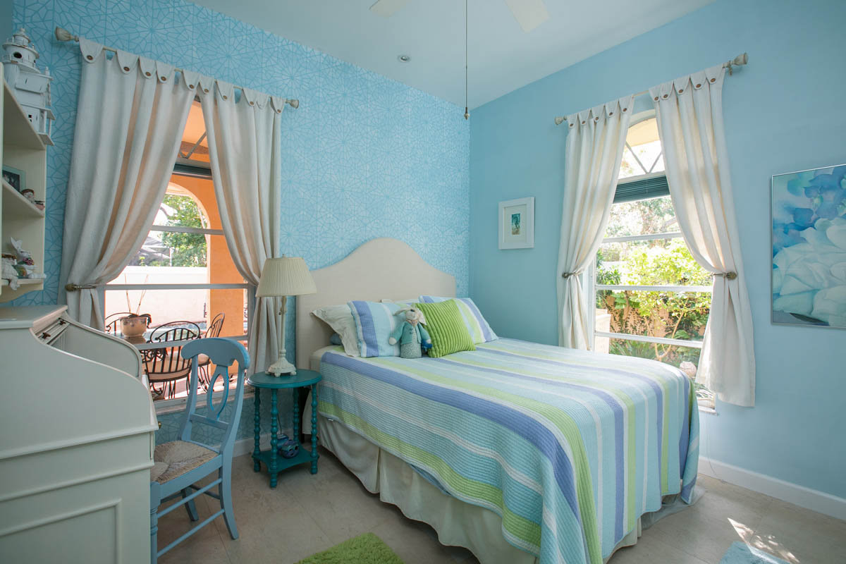 The third bedroom also has travertine tile floors and features a stenciled accent wall with views to the garden and pool area.  