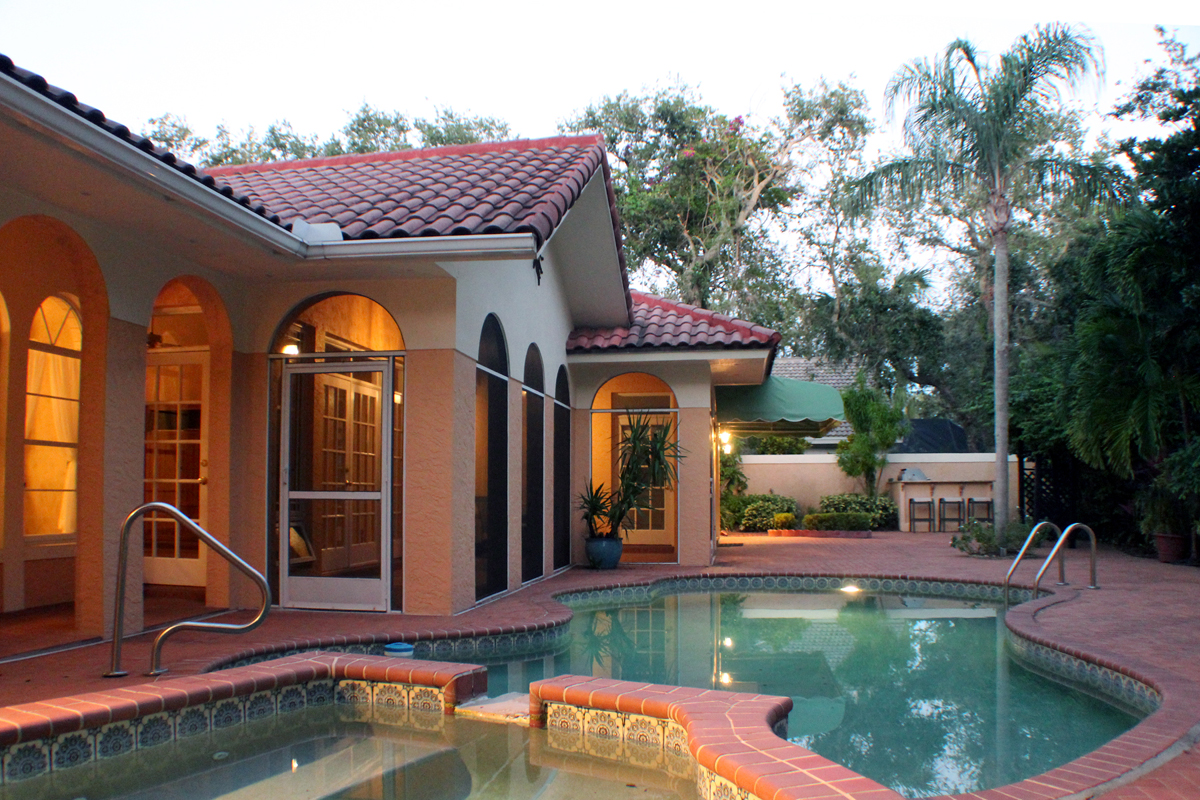 A view of the pool patio area and backyard at dusk.   