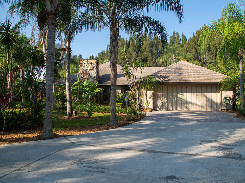 A view of the driveway to the garage and the front of the main house