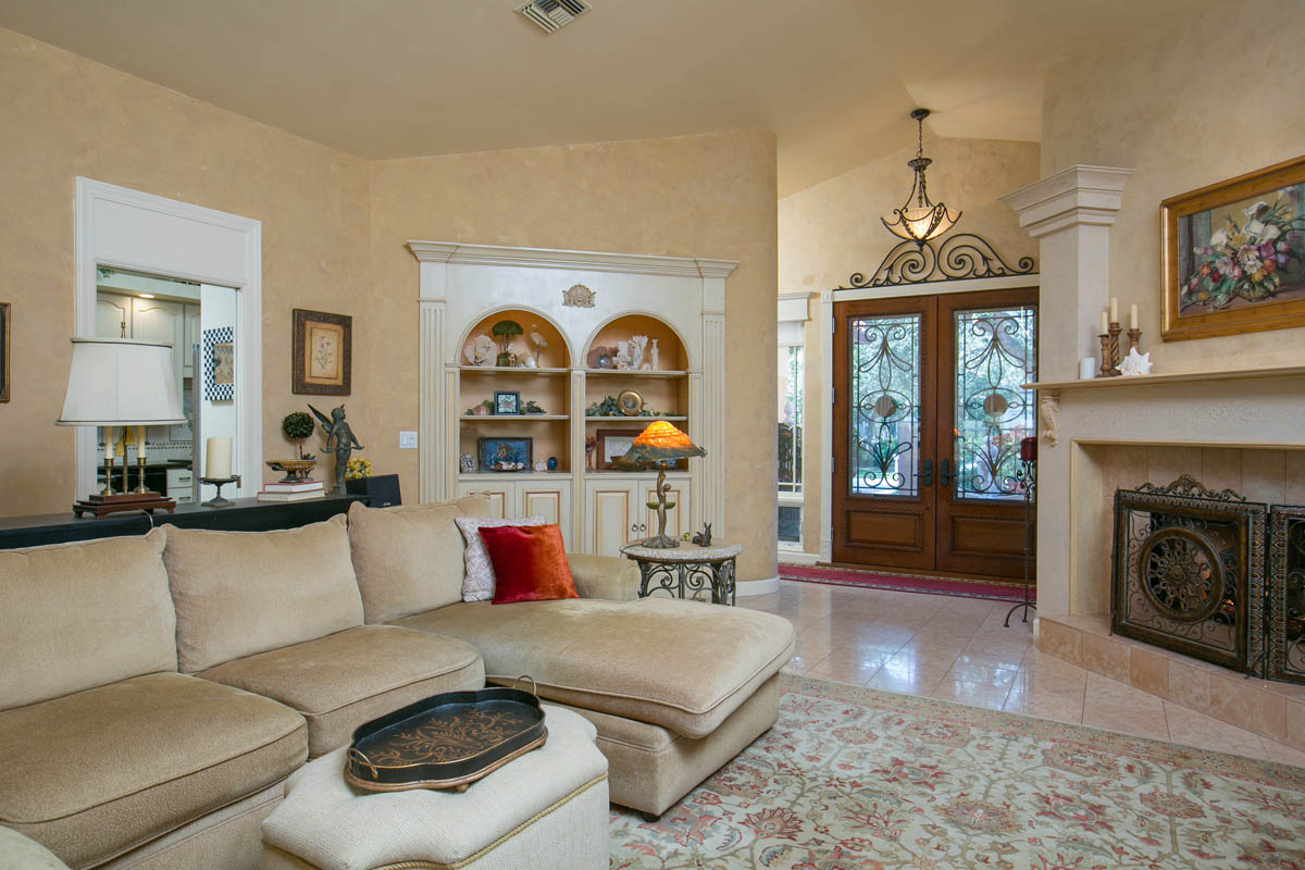 The grand living room features decoratively painted walls, marble floors, a fireplace and a built-in custom cabinet.     