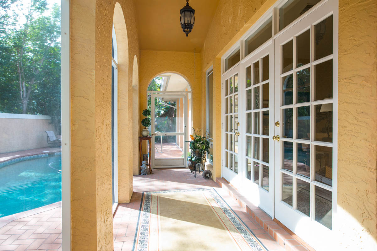 The covered and screen porch with pool views feature a custom painted floor design & a ceiling fan. n . 